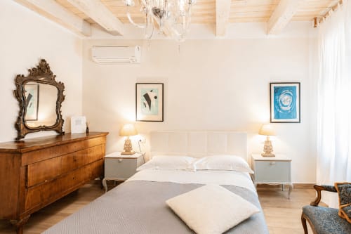 Camera da letto lussuosa presso Al Battistero Ravenna con letto queen size, cassettone in legno, specchio ornamentale e servizi moderni
