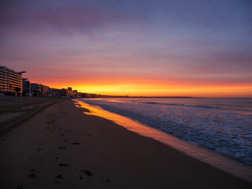 Sunset beach view at Hôtel Amirauté in La Baule with golden sky reflecting on sand and waves
