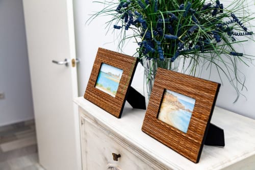 Marcos de madera con escenas de playa en cómoda con planta en maceta en el apartamento Barrosa Home de España