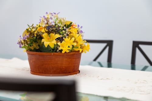 Flores amarillas y moradas vibrantes en maceta de barro sobre mesa en apartamento Barrosa Home con vista al océano