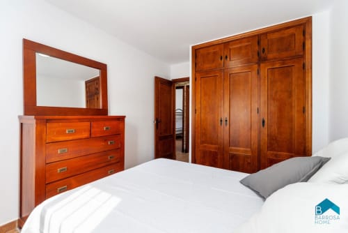 Dormitorio espacioso en villa Barrosa Home con muebles de madera, ropa de cama blanca y amplio armario
