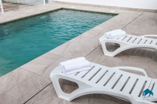 Dos tumbonas blancas con toallas blancas en la terraza de la piscina de terracota de la villa Barrosa Home en España