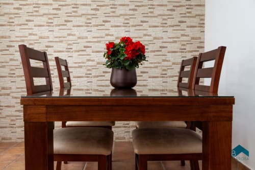 Mesa de comedor con sillas de madera y flores rojas en la villa apartamento Barrosa Home en España