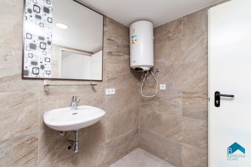 Baño moderno del apartamento Barrosa Home con lavamanos blanco, espejo y calentador de agua montado en pared