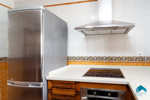 Cocina moderna en villa Barrosa Home con refrigerador de acero inoxidable, estufa, campana extractora, encimeras blancas y decorativa