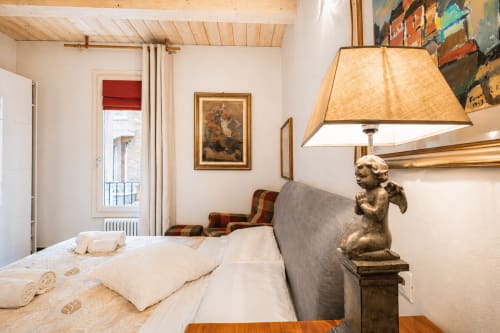 Elegante camera presso Al Battistero Luxury Suite a Ravenna con biancheria bianca, lampada cherubino, quadri incorniciati e vista sulla città