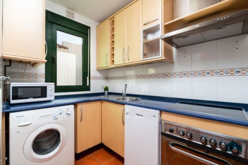 Cocina moderna en dúplex Barrosa Home con gabinetes de madera, encimeras azules y electrodomésticos de acero inoxidable