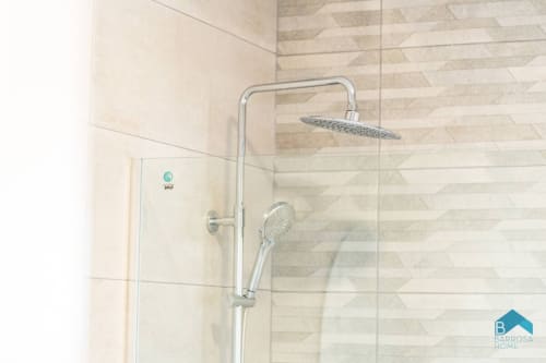 Moderno baño en villa Barrosa Home con ducha de efecto lluvia y alcachofa manual sobre pared de azulejos geométricos