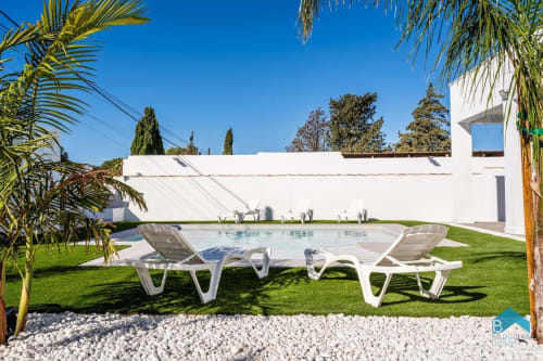 Villa blanca moderna con piscina, tumbonas y jardín cuidado en Barrosa Home, España