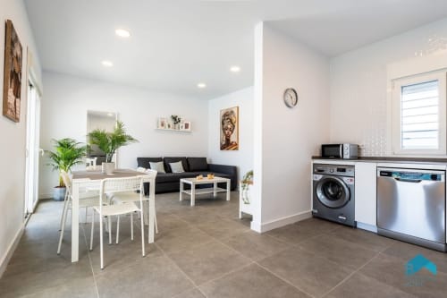 Cocina y sala de estar de planta abierta moderna en el apartamento Villa Granizo C de Barrosa Home con mesa de comedor y sofá negro