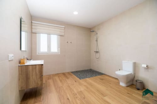 Baño moderno en Villa Bison A de Barrosa Home con tocador de madera, ducha amplia y sanitario
