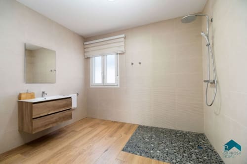 Baño moderno en Villa Bison A de Barrosa Home con vanidad de madera, ducha abierta y tonos neutros cálidos