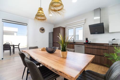 Cocina y comedor de villa moderna en Barrosa Home con mesa de madera, sillas oscuras y accesorios contemporáneos en España