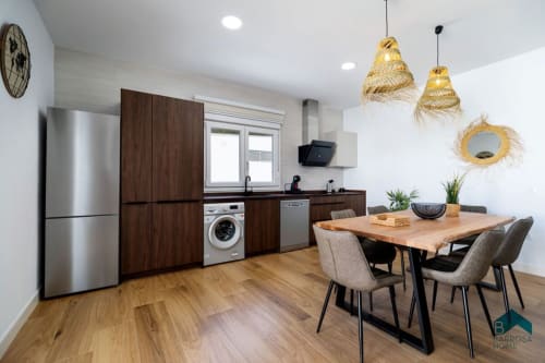 Moderna sala de cocina-comedor en Villa Bison A de Barrosa Home con gabinetes de madera, electrodomésticos de acero inoxidable y luz natural