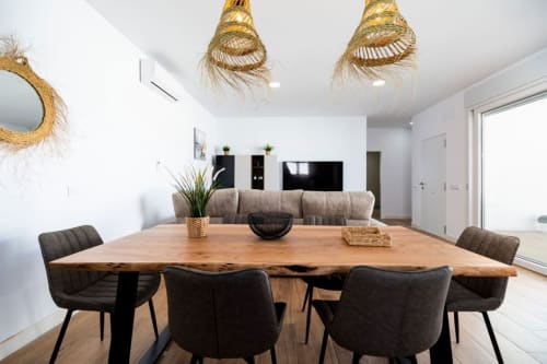 Comedor moderno en Villa Bison A de Barrosa Home con mesa de madera, sillas oscuras y lámparas colgantes tejidas