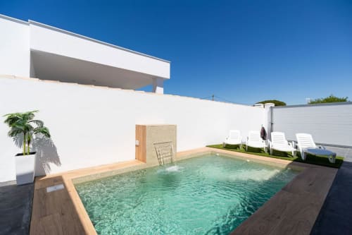 Villa moderna con piscina turquesa, tumbonas blancas y arquitectura minimalista en Barrosa Home, España