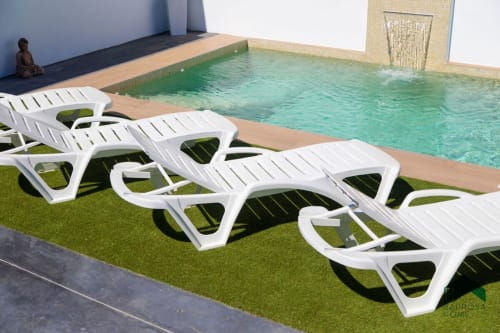 Tumbonas junto a la piscina y piscina turquesa en la villa Barrosa Home en España