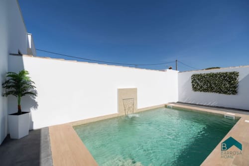 Villa Barrosa con piscina turquesa, patio de muros blancos y palmera bajo cielo azul