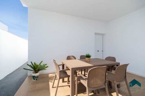 Terraza moderna de la villa Barrosa Home con mesa de comedor, sillas de mimbre, maceta y vistas al océano