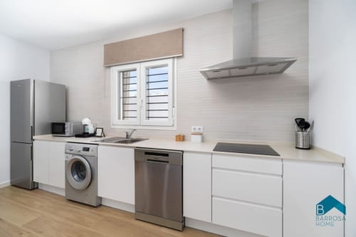 Cocina moderna de Villa Bisonte B en Barrosa Home con electrodomésticos de acero inoxidable, gabinetes blancos y piso de madera