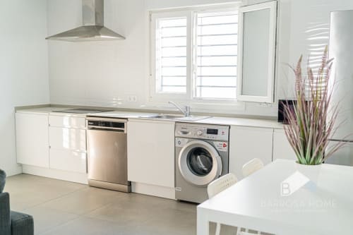 Cocina moderna de la villa Barrosa Home con electrodomésticos de acero inoxidable, gabinetes blancos e isla central