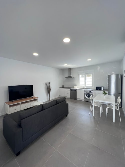 Apartamento moderno diáfano en Villa Granizo, Barrosa Home con sofá negro, cocina, comedor y sala de televisión