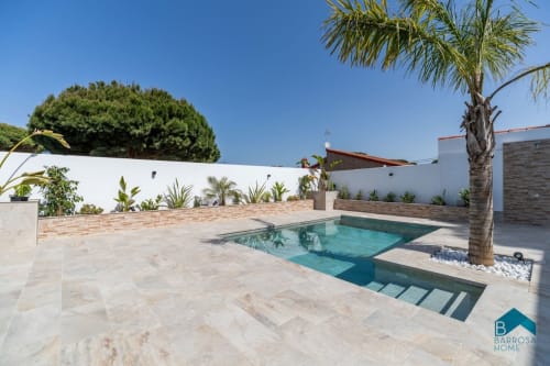 Apartamento Barrosa con piscina moderna, palmera, terraza y paredes blancas en España