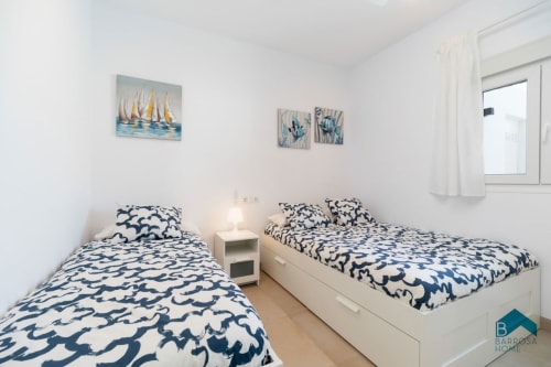Dormitorio doble con ropa de cama de patrón azul marino en apartamento Barrosa Home en España, decoración náutica