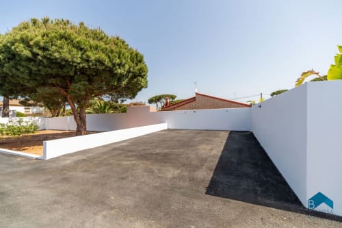 Amplia terraza del apartamento Barrosa Home con paredes blancas, árbol maduro y cielo despejado
