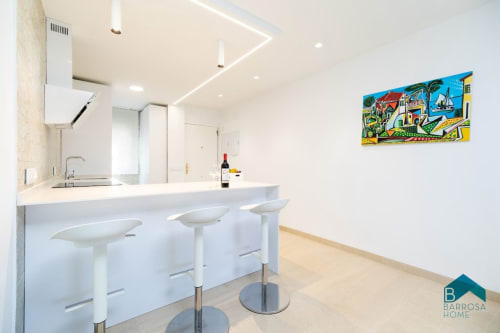 Cocina blanca moderna con barra en el apartamento Barrosa Home en España, con acabados contemporáneos y coloridos