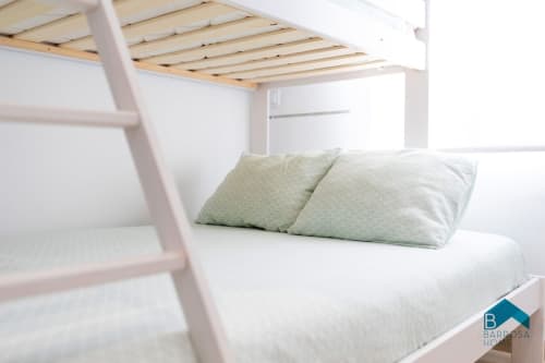 Cama litera blanca brillante con almohadas verdes en el apartamento Barrosa Home en Aldea del Coto, España