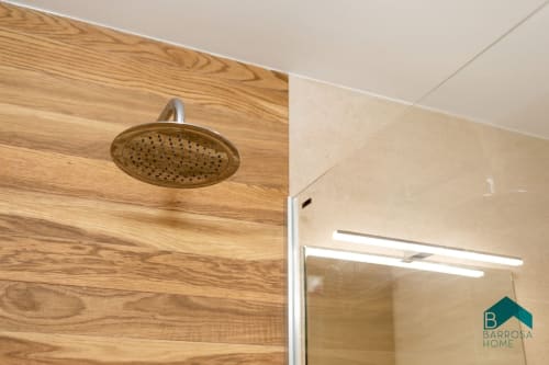 Moderno baño con ducha tipo lluvia y paredes de madera en el apartamento Barrosa Home en España