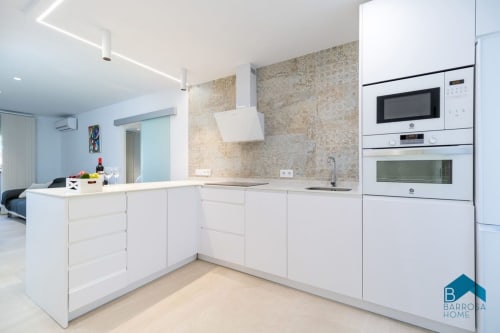 Cocina moderna y luminosa en apartamento Barrosa Home con backsplash de granito, isla central y electrodomésticos empotrados