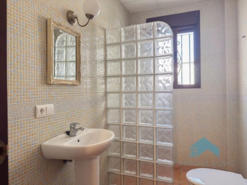 Baño moderno de la Villa Alba Barrosa con muro de ducha de bloques de vidrio, lavamanos de pedestal y pequeña ventana