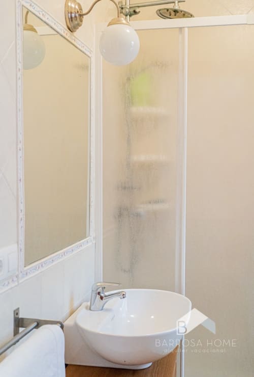 Baño moderno en villa Barrosa Home con lavabo redondo blanco, mampara de ducha y accesorios de latón