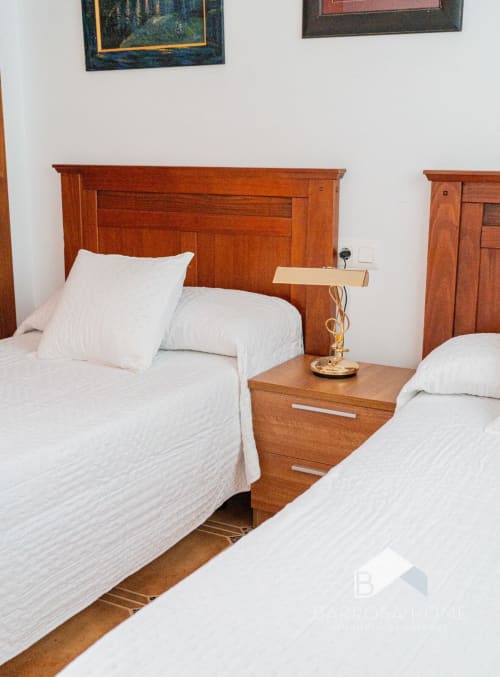 Dormitorio doble con muebles de madera y ropa de cama blanca en la villa Barrosa Home en España