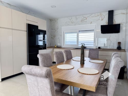 Cocina y comedor modernos en Villa Horizonte de Barrosa Home con paredes de mármol, muebles color crema y sillas tapizadas