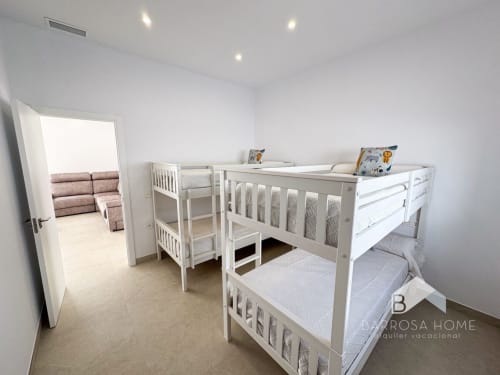 Literas blancas en la luminosa habitación infantil del apartamento Barrosa Home Villa Horizonte en España