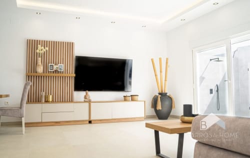 Sala de estar moderna en Barrosa Home con televisor, muebles de madera y decoración contemporánea