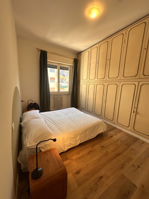 Camera da letto luminosa a Funari Tuscany Stays a Firenze con letto bianco, armadio in legno e vista sugli edifici della città