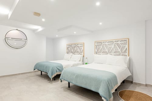 Habitación doble moderna en Barrosa Home con dos camas, cabeceros con diseño de hojas, mantas azul claro y techo contemporáneo