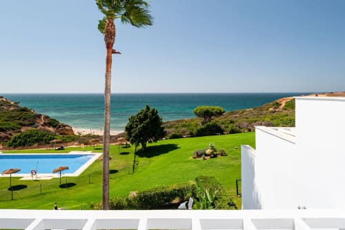 Apartamento Barrosa con piscina, jardín impecable, palmera y vistas costeras turquesas