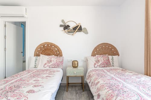 Dos camas gemelas con ropa de cama estampada en rosa en el apartamento Barrosa Home en España, con cabeceros tejidos y decoración minimalista