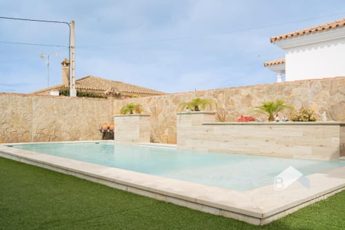 Villa moderna con piscina en Barrosa Home, muros de piedra, tumbonas y jardín impecable en España