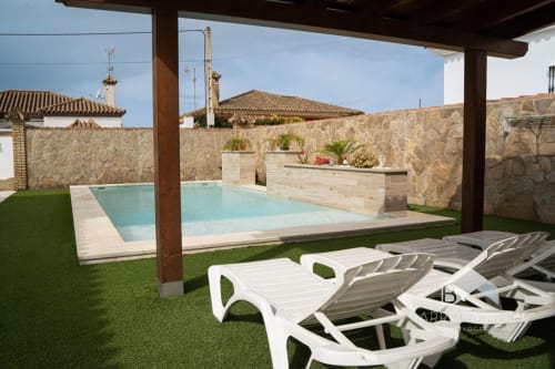 Piscina de lujo con tumbonas, muros de piedra y jardín diseñado en Barrosa Home, España