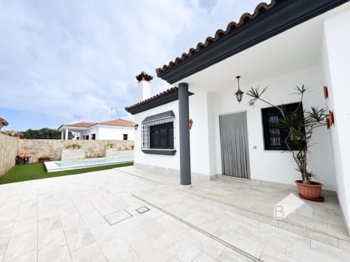 Patio de Villa Cañuela con terraza, piscina y muros blancos en Barrosa Home, España