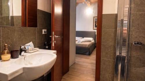 Bagno con lavabo bianco e pareti in piastrelle marroni nella Triple Comfort Room di Al Battistero Luxury Suite, Ravenna