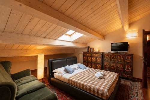 Spaziosa camera da letto in soffitta presso Al Battistero Luxury Suite a Ravenna con travi in legno, letto nero e mobili decorativi