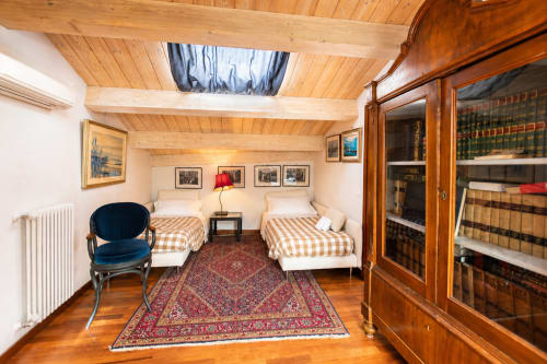 Accogliente camera familiare presso Al Battistero Luxury Suite a Ravenna con due letti, travi in legno, libreria e arredi d'epoca