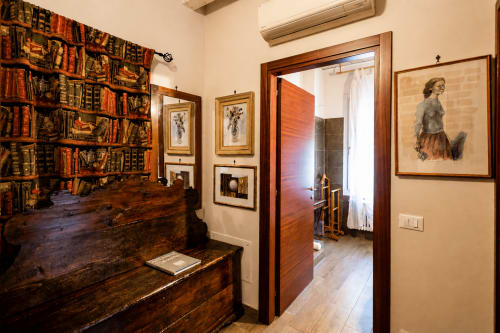Elegante ingresso suite presso Al Battistero a Ravenna con antica scrivania in legno, opere d'arte incorniciate e arredi classici italiani